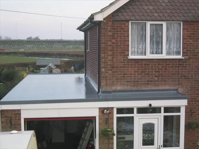 Smooth grey flat roof on a single storey extension at the back of a red brick house
