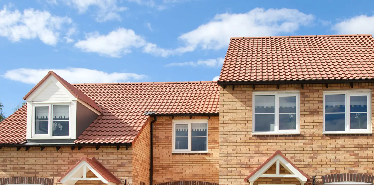 Row of new brick houses with red tiled roofs and dormer windows