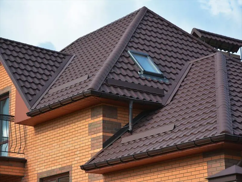Brown concrete tiled roof with a roof window on a red brick house