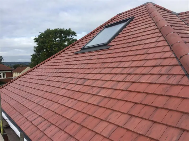Red tiled pitched roof with a roof window above a brick house