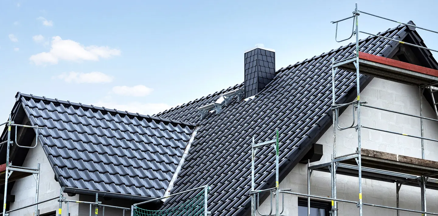 Dark tiled roofs on new houses with scaffolding along the gable end